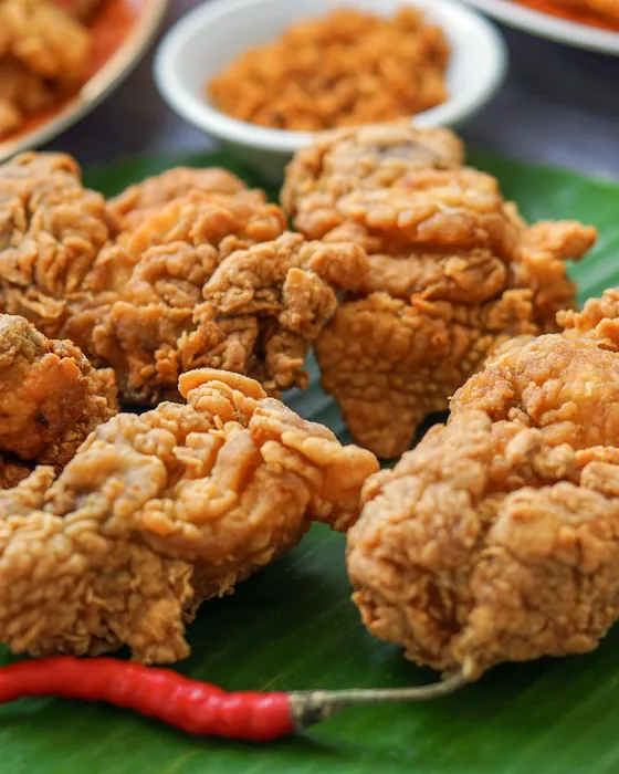 Ayam goreng krispi di atas daun pisang dengan cabai merah (foto ilustrasi)