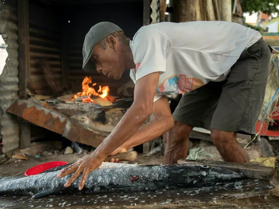 Seorang bapak membakar ikan di atas bara (foto ilustrasi)